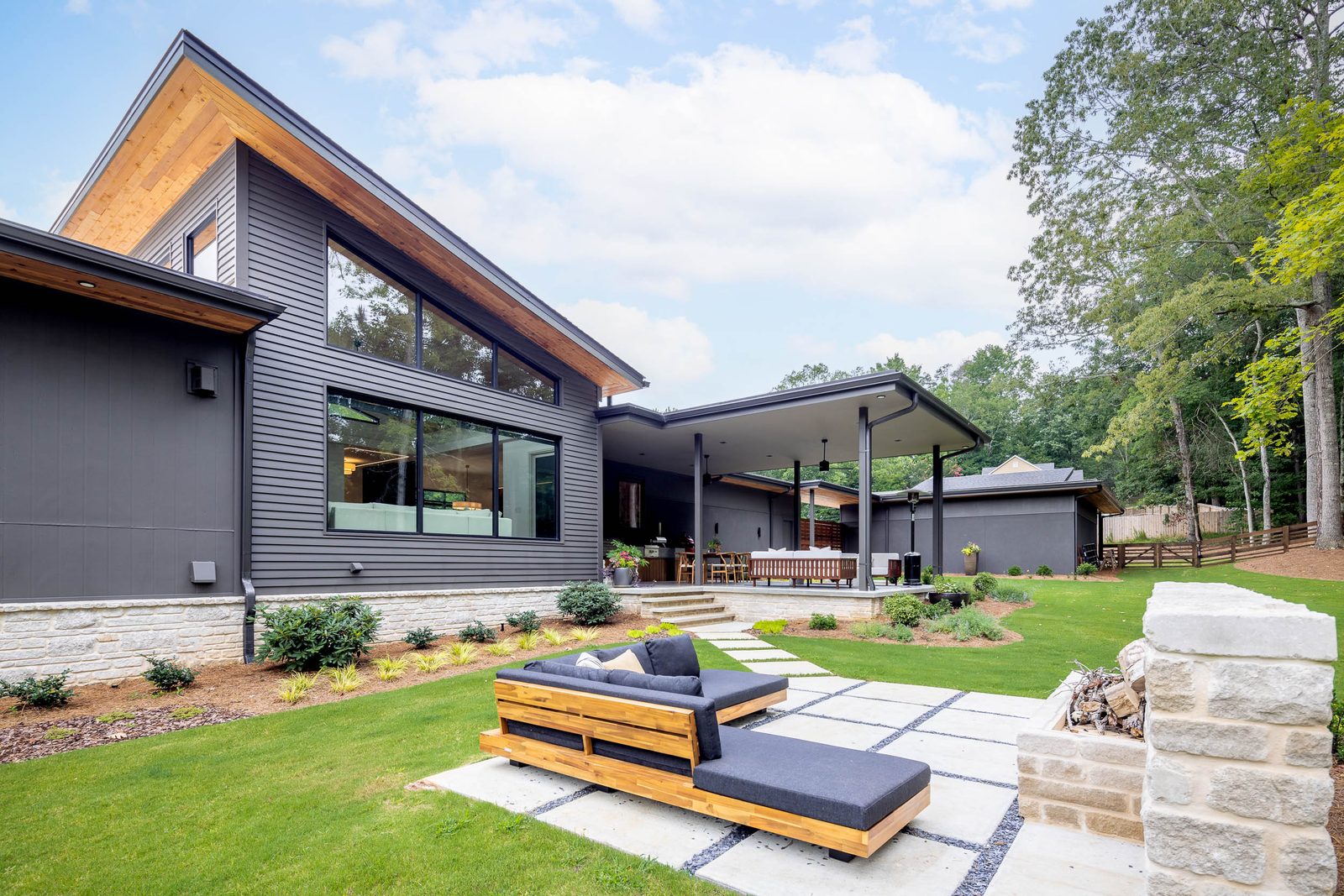 Rear paver patio with sun loungers and stone seat walls — The Ortiz Home, custom home built by Ironwood Construction Group in Sugar Hill, Georgia