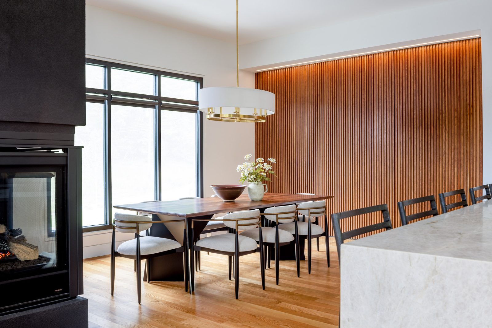 Dining area with slat-wood wall and two-sided fireplace — The Ortiz Home, custom home built by Ironwood Construction Group in Sugar Hill, Georgia