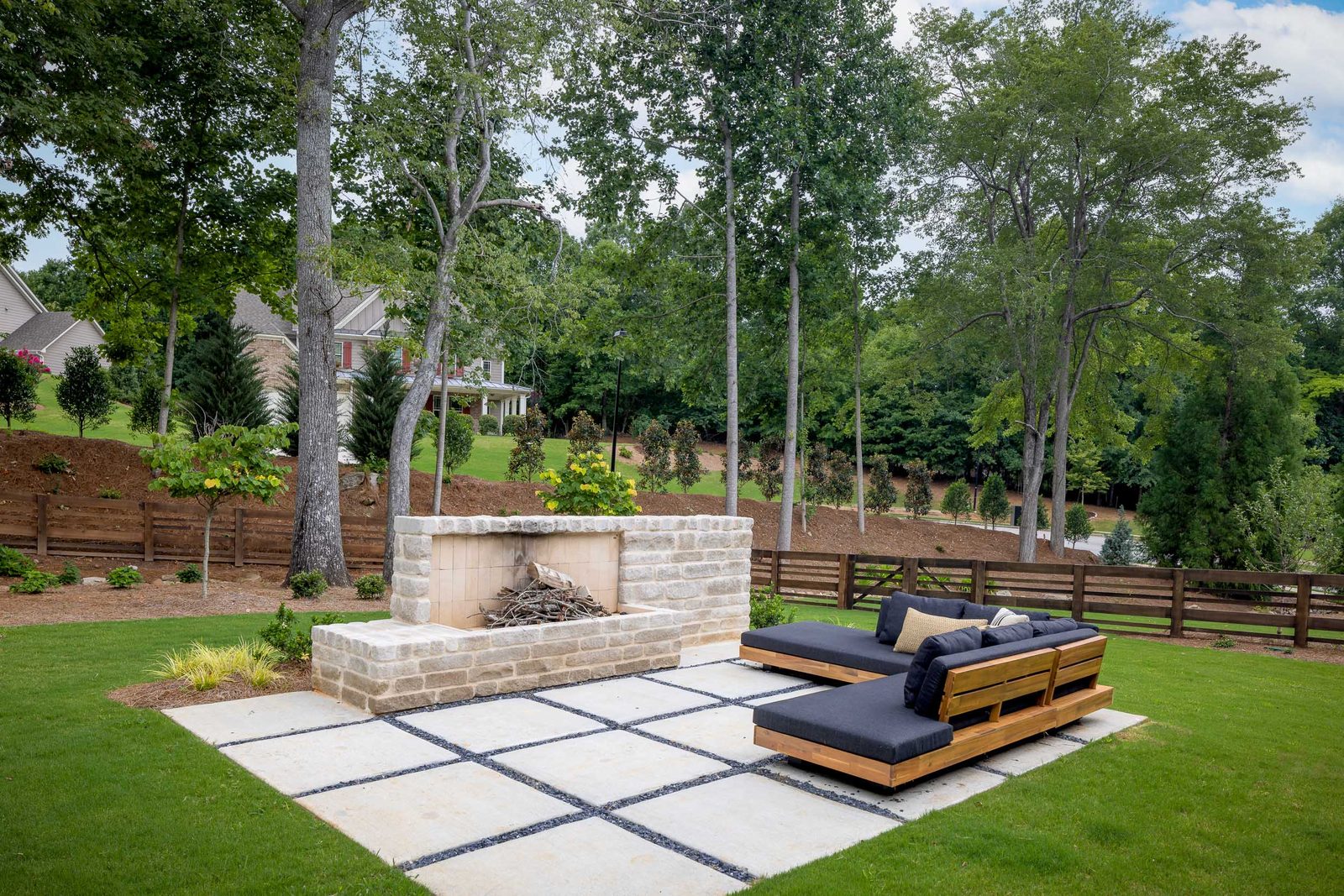 Paver patio with sun loungers and stone fire feature — The Ortiz Home, custom home built by Ironwood Construction Group in Sugar Hill, Georgia