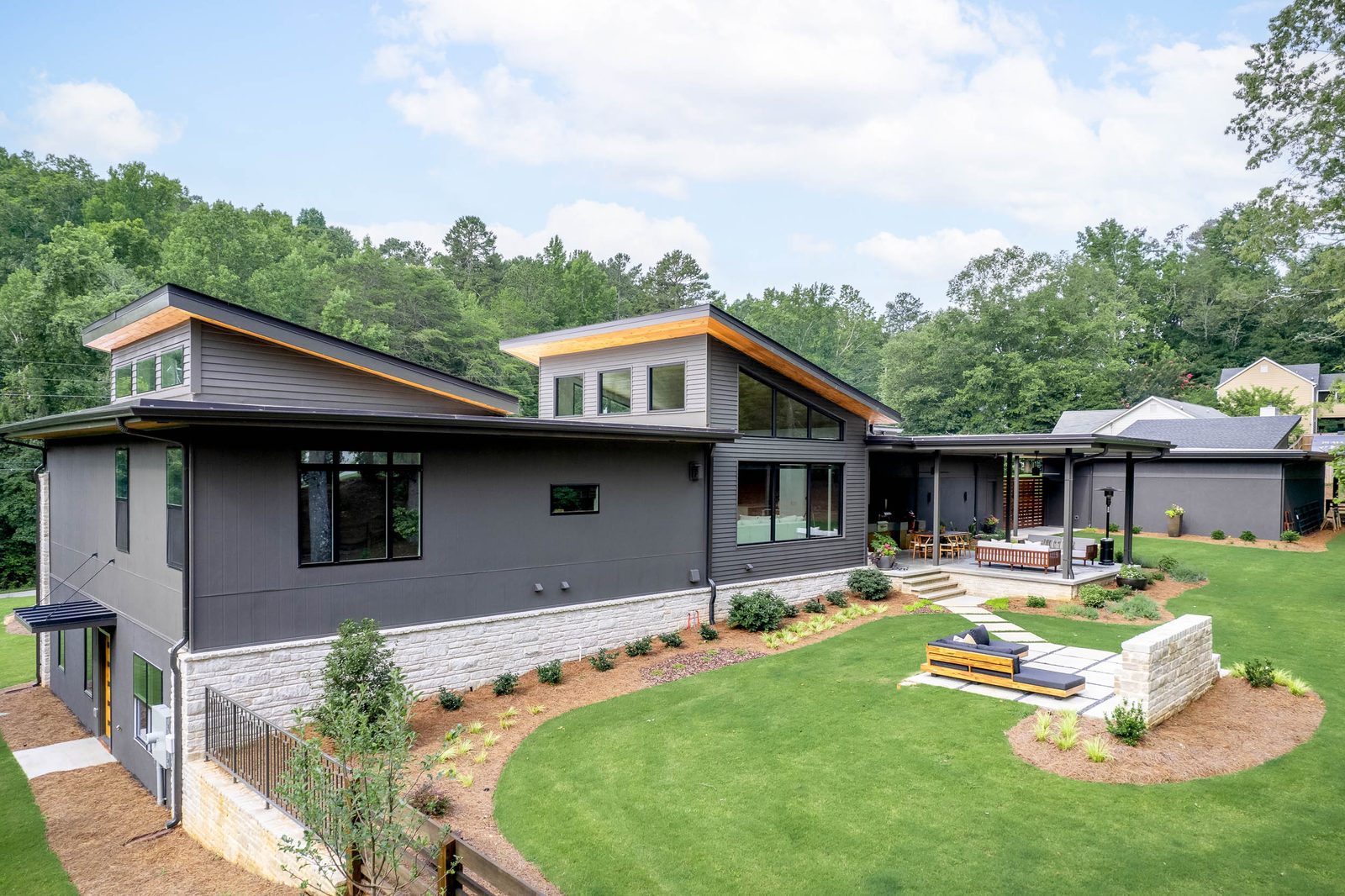 Rear elevation across the lawn with the fire-pit lounge — The Ortiz Home, custom home built by Ironwood Construction Group in Sugar Hill, Georgia
