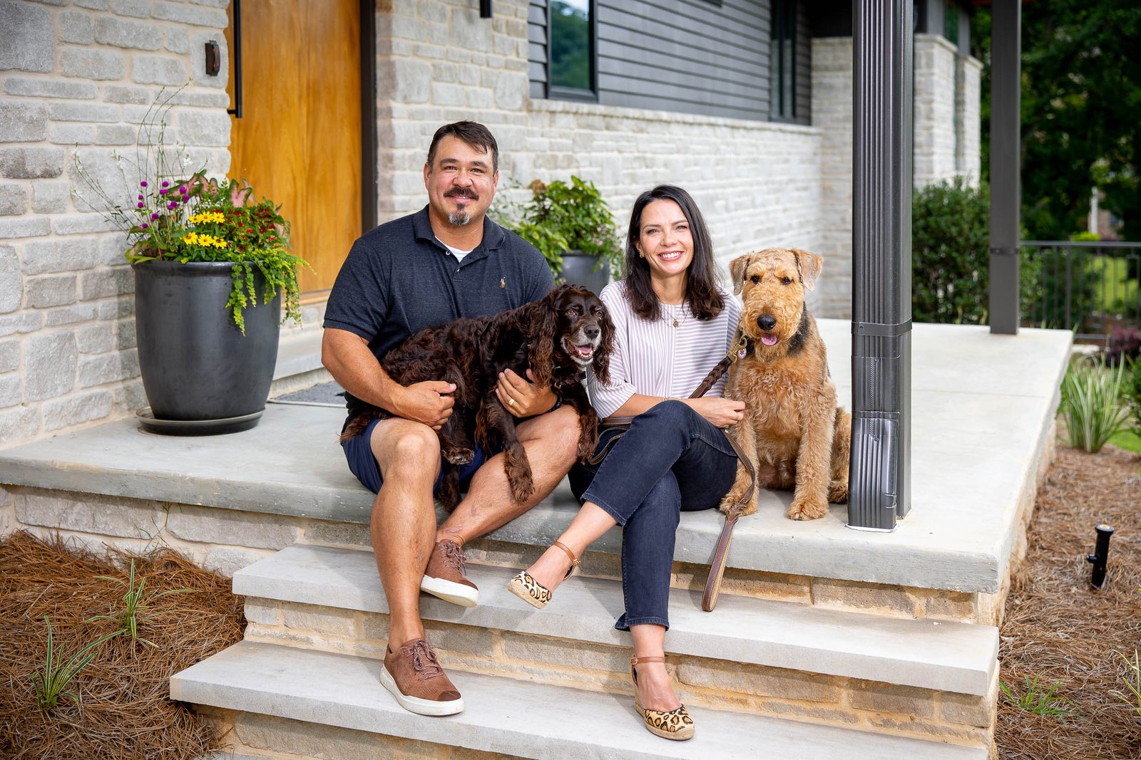 The homeowners and their dogs on the front steps — The Ortiz Home, custom home built by Ironwood Construction Group in Sugar Hill, Georgia