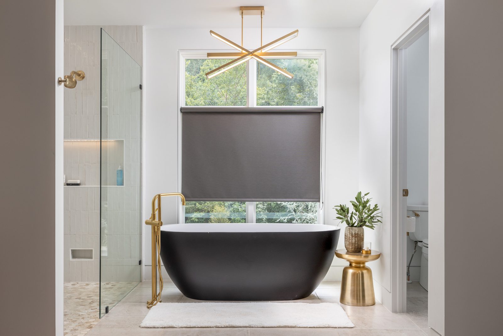 Freestanding black soaking tub with brass floor filler — The Ortiz Home, custom home built by Ironwood Construction Group in Sugar Hill, Georgia