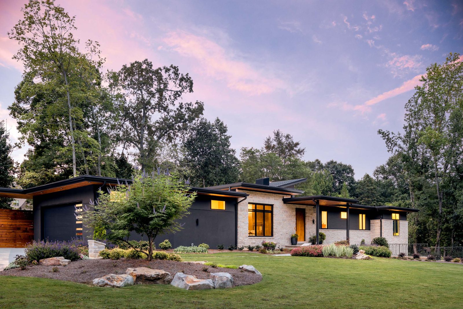 Twilight elevation framed by the surrounding trees — The Ortiz Home, custom home built by Ironwood Construction Group in Sugar Hill, Georgia