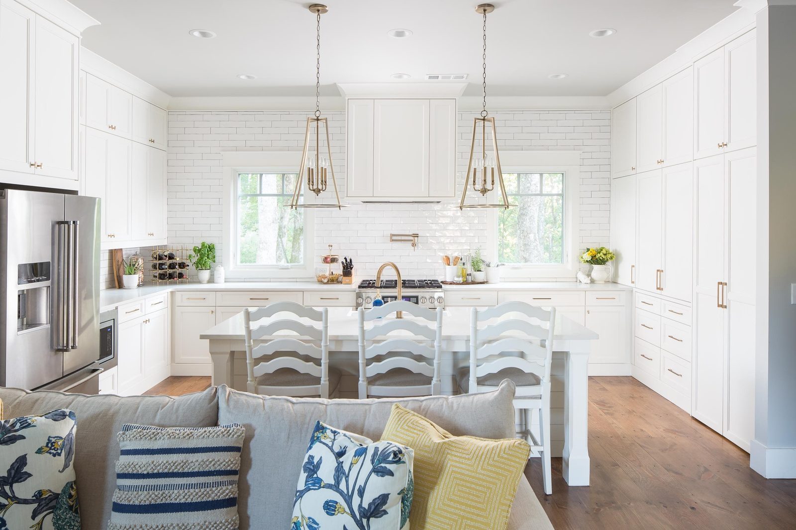 Kitchen with white cabinetry, island seating and brass pendants — Austin Garner Rd, custom home built by Ironwood Construction Group