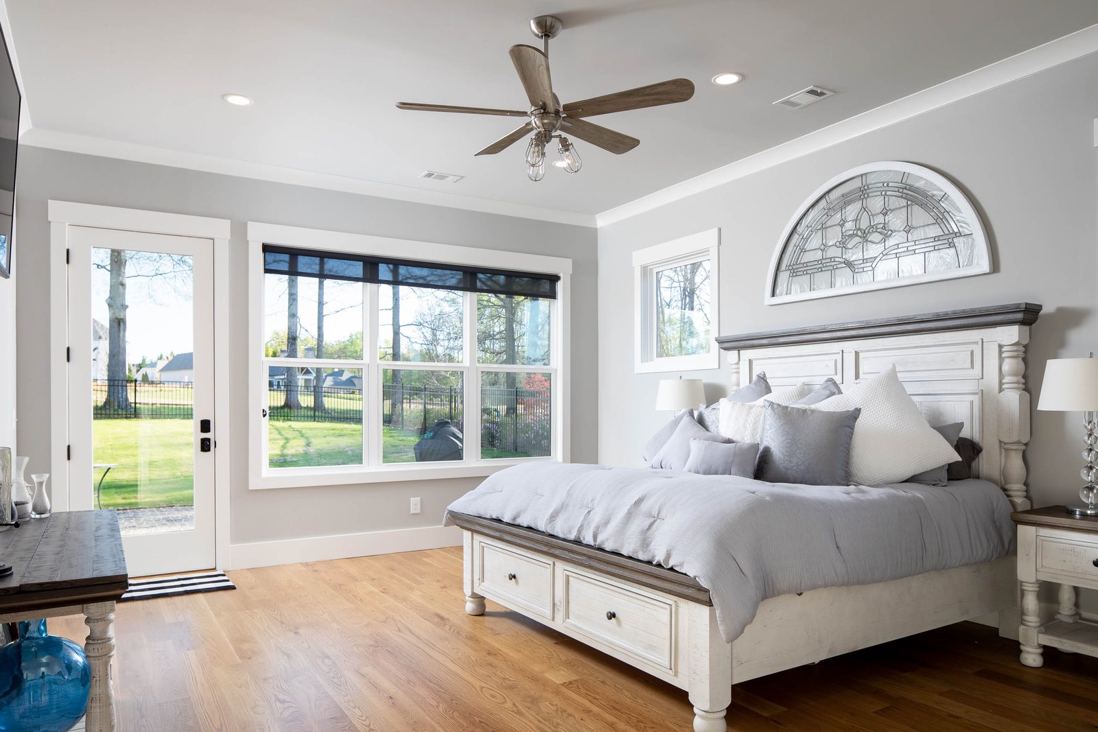 Primary bedroom with arched transom window and ceiling fan — Glausier, custom home built by Ironwood Construction Group