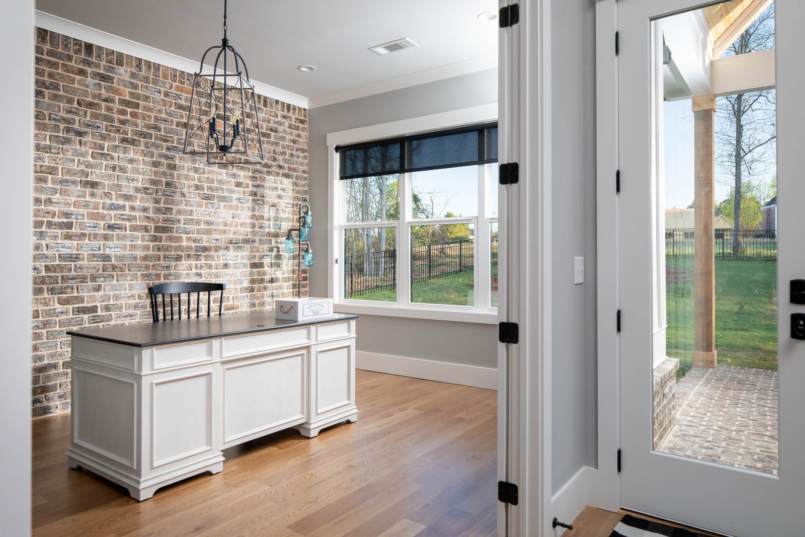 Kitchen with exposed brick wall and white island — Glausier, custom home built by Ironwood Construction Group