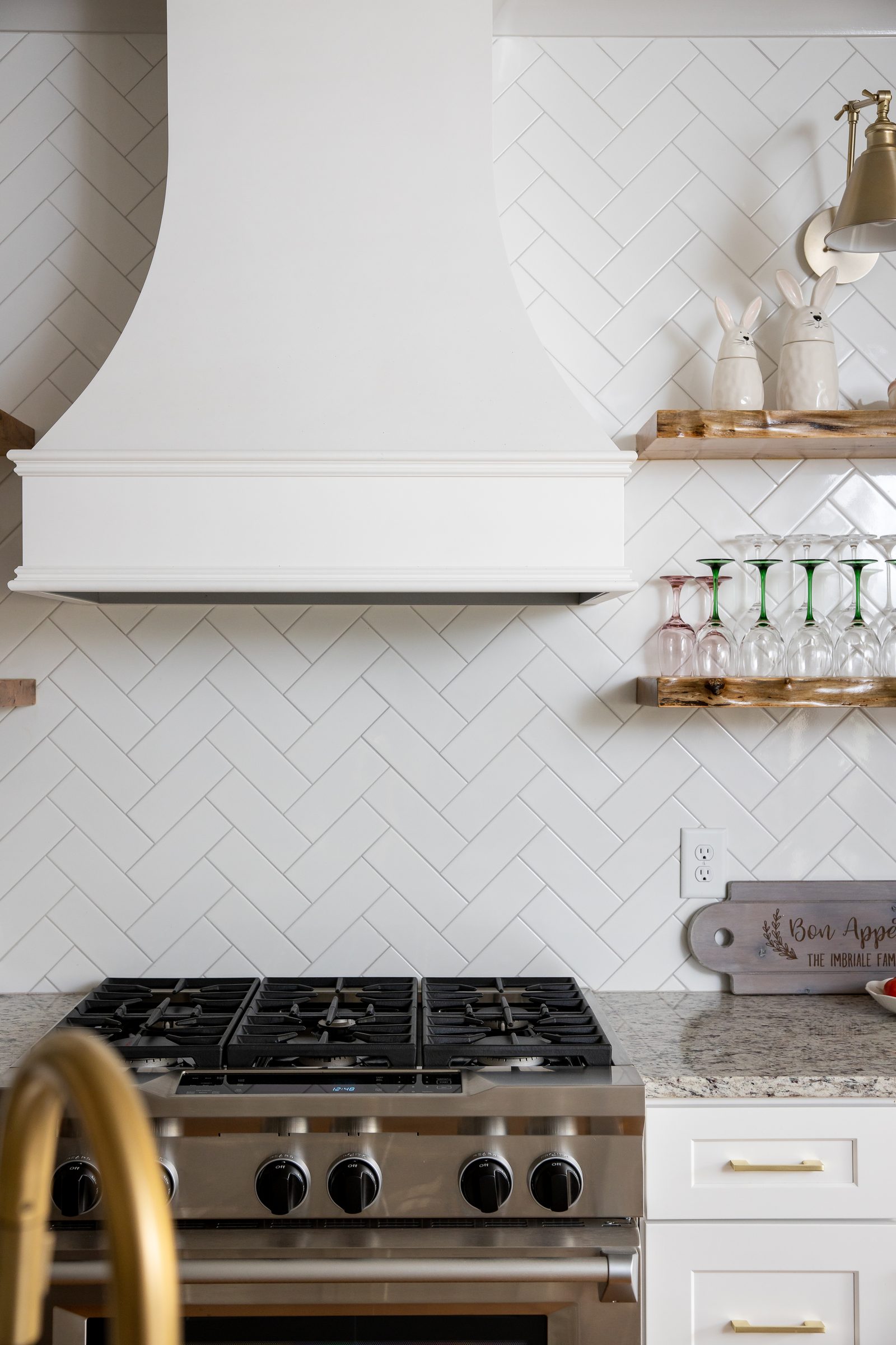 Gas range beneath the white hood with herringbone tile — Imbriale, custom home built by Ironwood Construction Group