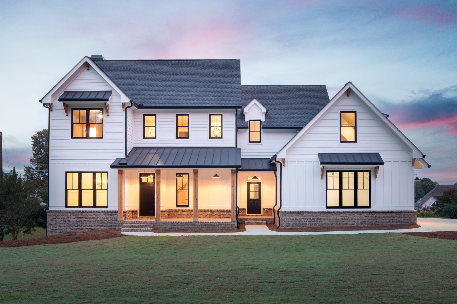 Front elevation at dusk with warm interior lighting — Shadburn Ferry, custom home built by Ironwood Construction Group in Buford, Georgia