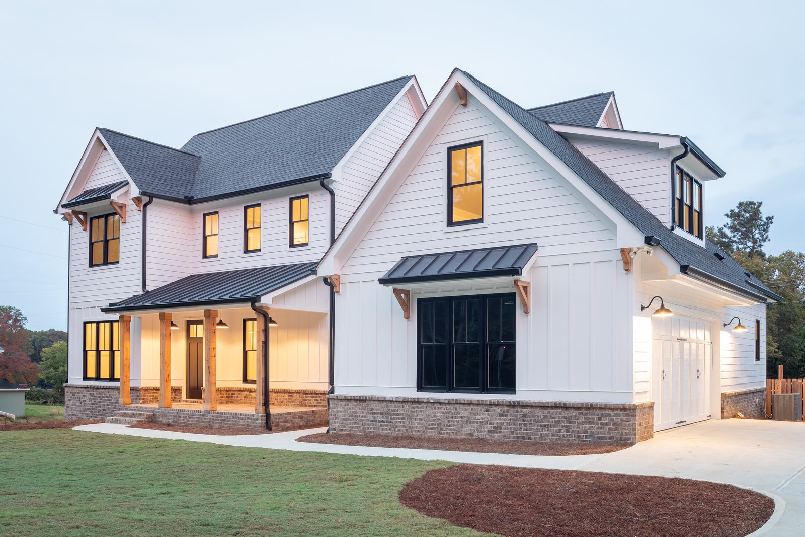 Front elevation at dusk with covered porch and side-entry garage — Shadburn Ferry, custom home built by Ironwood Construction Group in Buford, Georgia